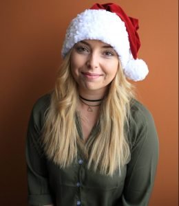 Jessica sitting with Santa hat on smiling
