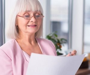 Elderly woman with glasses reading her accessible healthcare documents