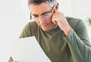 Image of man wearing glasses reading personal customer correspondence documents.
