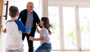 Image of senior wearing eye glasses depicting the low vision demographic; he’s dancing with young family members.